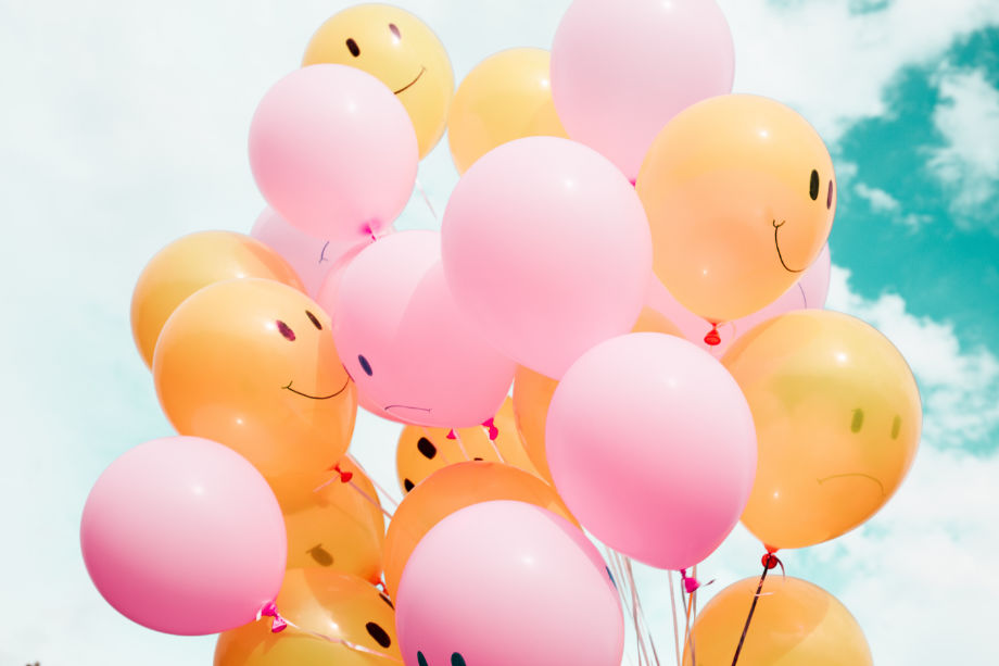 Produktivität und Selbstwachstum - Ein Bündel bunter Luftballons mit lachendem Gesicht.